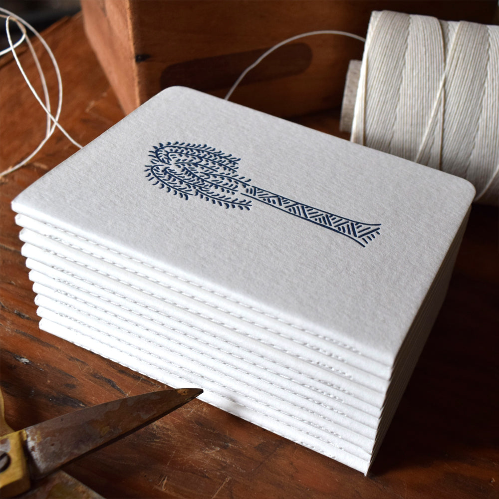Stack of white notebooks with a blue design on a wooden surface