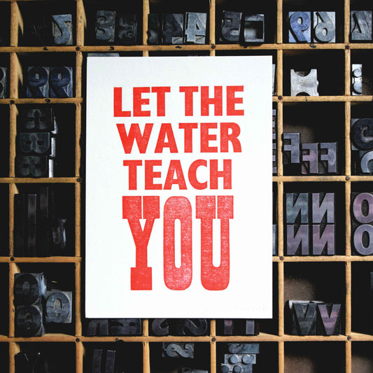 White paper with red text 'LET THE WATER TEACH YOU' surrounded by letterpress printing blocks.